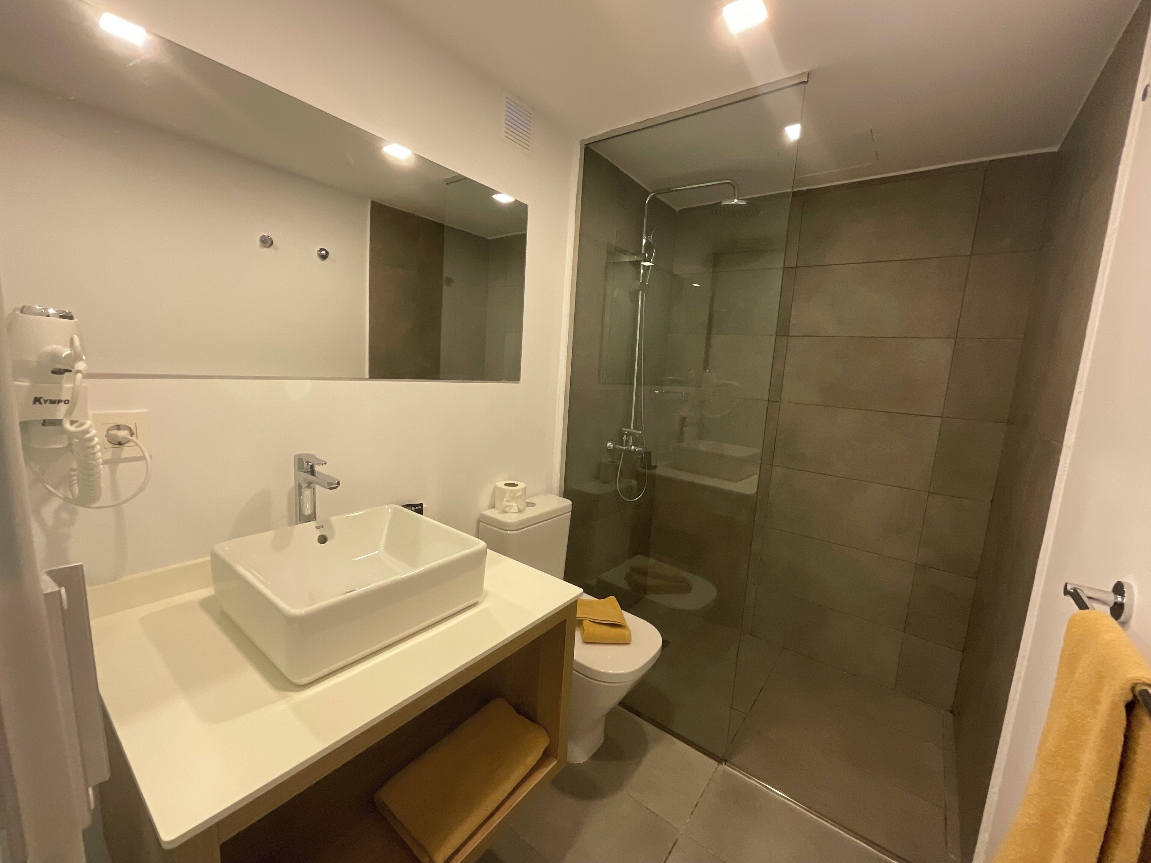 Un bagno moderno con lavandino bianco, specchio e cabina doccia in vetro.