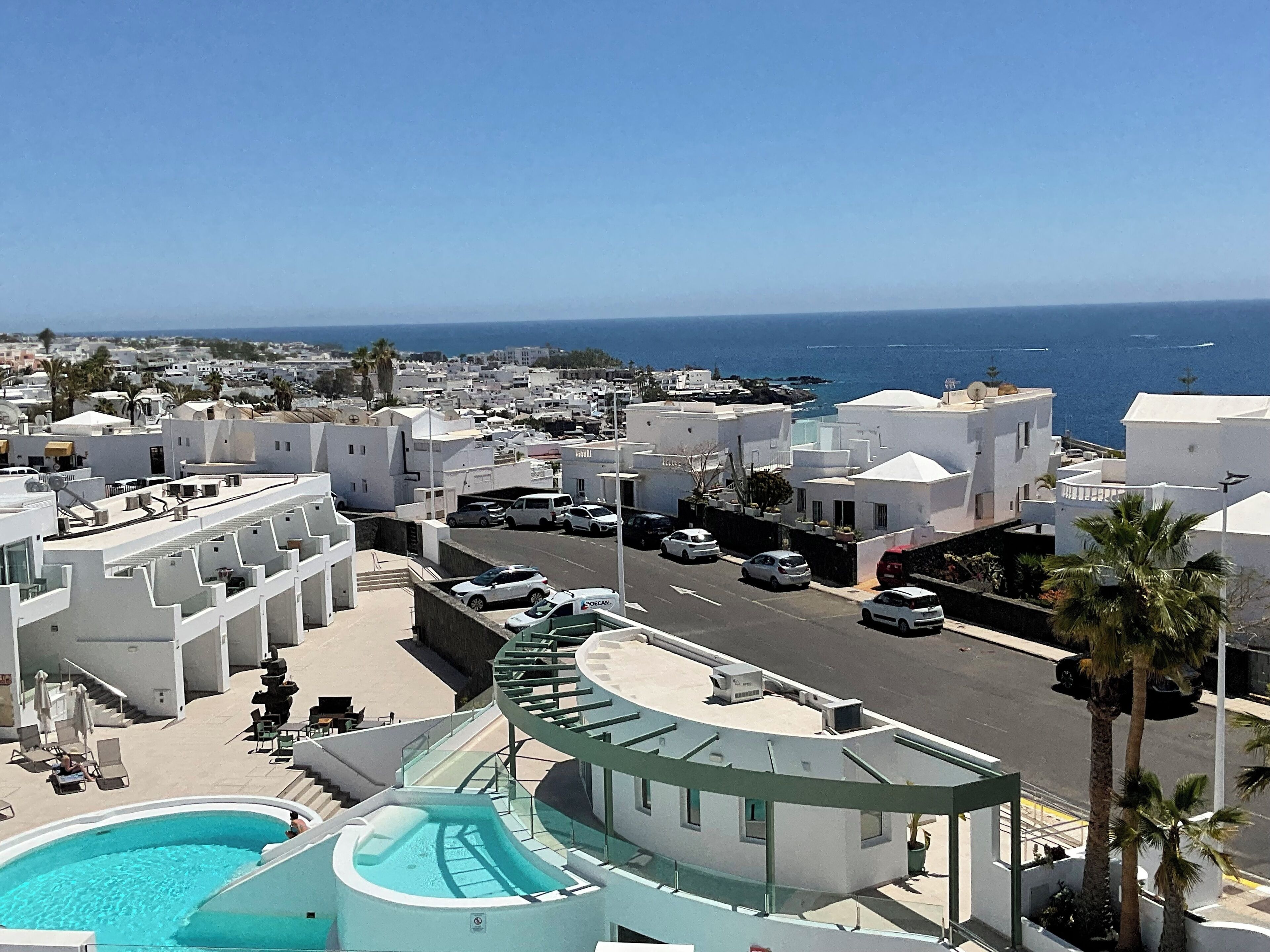 Un pueblo costero con edificios blancos, zona de piscina y vista despejada al mar.