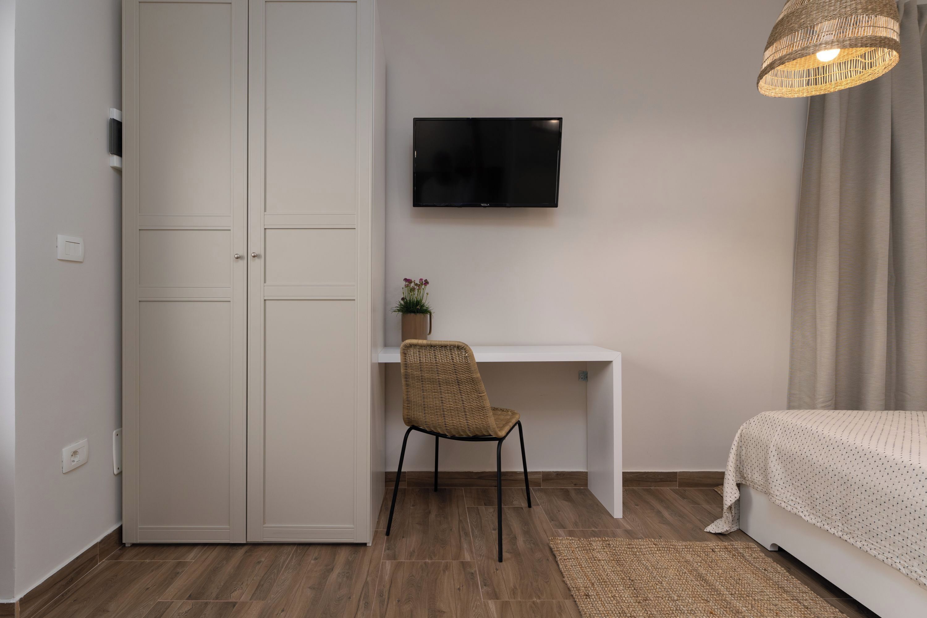 A bedroom with a bed, a desk, a chair, a TV, and a wardrobe.