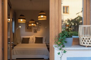 A bedroom with a bed, bedside lamps, a potted plant, and a wicker chair. - Studio apartment Alloro Three (Istria - Novigrad) (Novigrad)
