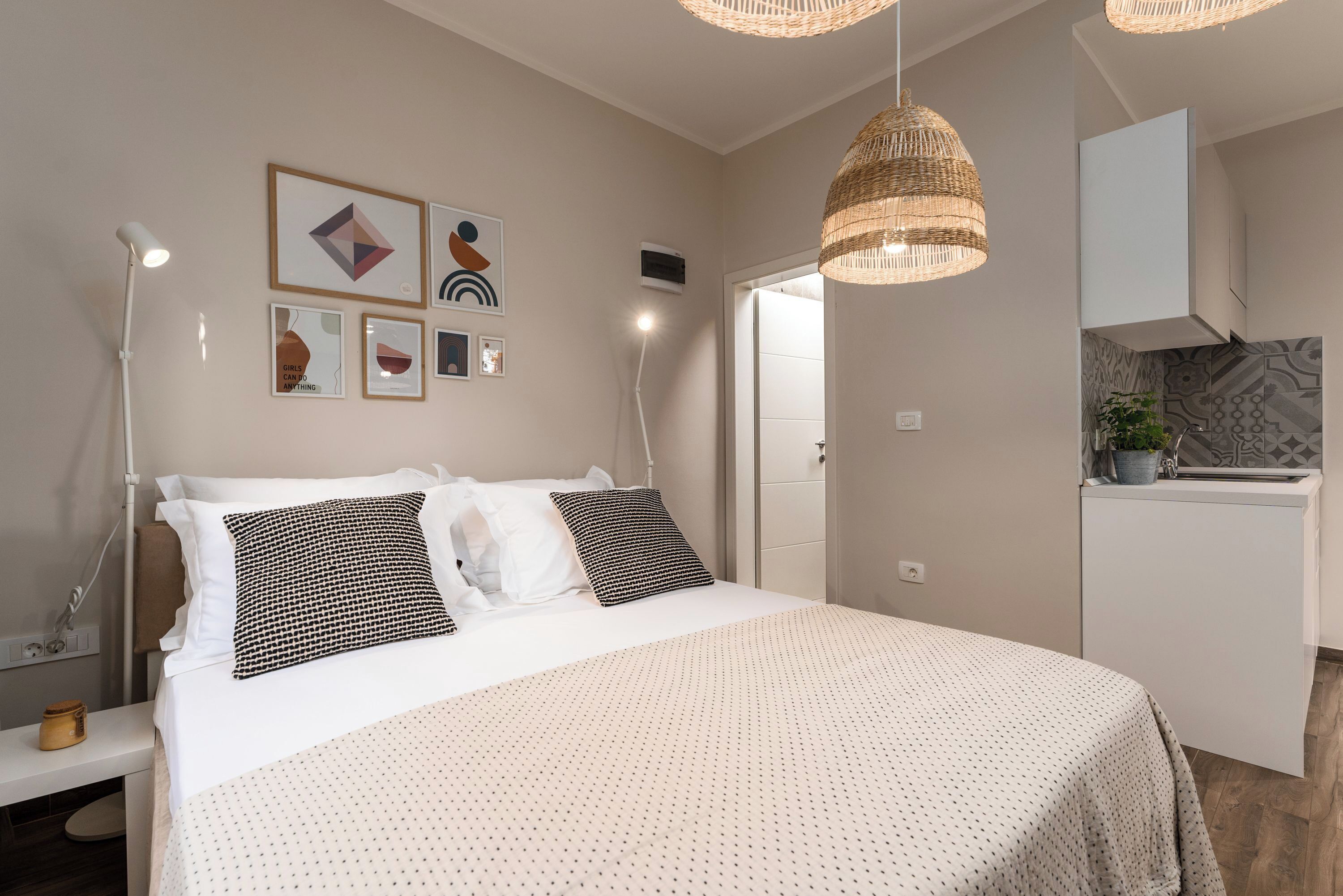 Un dormitorio ordenado con cama, lámparas de noche y una pared decorada con cuadros.