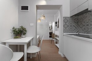 A modern kitchen with white cabinetry, a dining area with a white table and chairs, and a patterned backsplash.