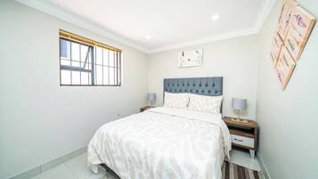 A bedroom with a bed, nightstands, a window, and a wall art piece.