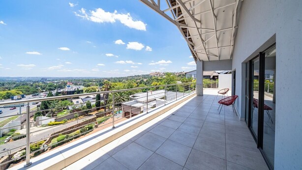 A balcony with a view of a cityscape, a tiled floor, and red chairs. - Ada 5 (Bedfordview)