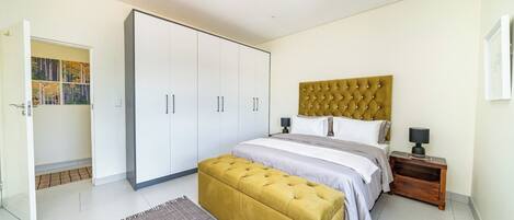 A bedroom with a bed, a large wardrobe, a bedside table, and a floor lamp.