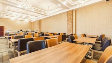 A conference room with multiple tables and chairs, a chandelier, and a stone accent wall.