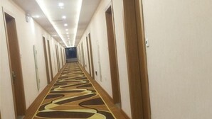 Un pasillo de hotel con alfombra estampada, puertas de madera e iluminación empotrada en el techo.