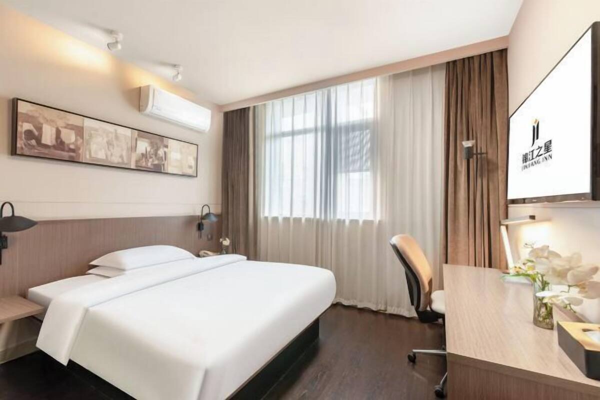 Habitación de hotel con una cama grande, un escritorio, una silla y una ventana con cortinas.