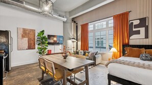 Een moderne hotelkamer met een zithoek, een groot bed en een televisie aan de muur.