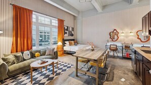 Een moderne hotelkamer met een bed, een bank, een eettafel en een kitchenette.