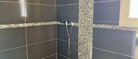 A shower area with dark tiles and a mosaic border.