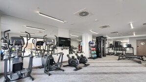 A modern gym with various cardio machines, weightlifting equipment, and a large mirror. - Livensa Living Salamanca Parking Free (Salamanca)
