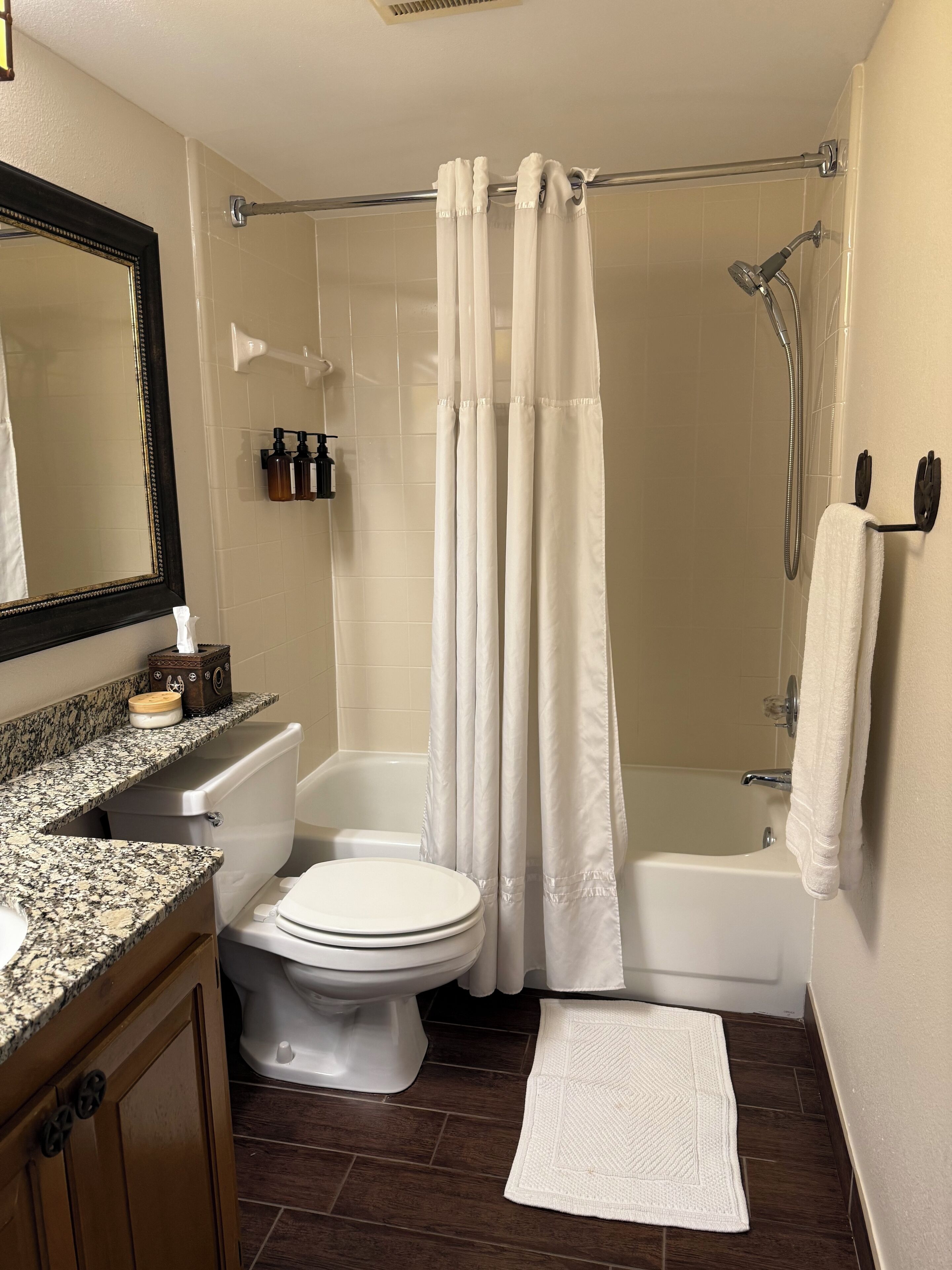 Un bagno con toilette, lavandino, specchio, doccia e vasca da bagno.