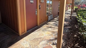 A covered walkway with stone flooring, wooden walls, and numbered doors. - Cozy 1-bedroom condo with WiFi, AC in lovely Westgate River Ranch (River Ranch)