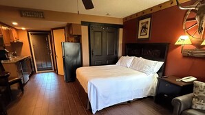 A hotel room with a bed, a desk, a chair, a ceiling fan, and a door. - Cozy 1-bedroom condo with WiFi, AC in lovely Westgate River Ranch (River Ranch)