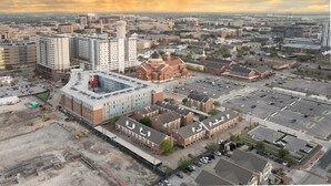 An aerial view of a cityscape with various buildings, including a large church with a dome, a parking lot, and construction sites. - Camellia: Studio Apt, 4 Minute walk to A&M (College Station)