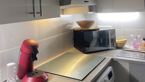 Una cocina moderna con armarios blancos, microondas, tostadora y lavadora.