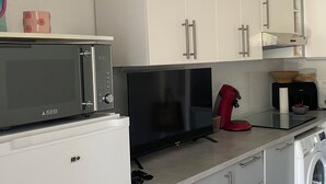 Una kitchenette compacta con microondas, tostadora y lavadora.