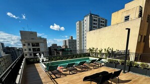 Un espace piscine aménagé sur le toit, avec un sol en bois, des chaises longues et une piscine.