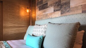 A bed with patterned pillows, a wooden headboard, and a hanging light fixture. - 1 Bed With Ocean Front Views in the Romantic Zone - C205 (Puerto Vallarta)
