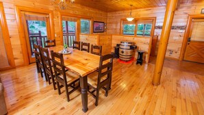 A wooden interior with a dining table, chairs, and a barrel.