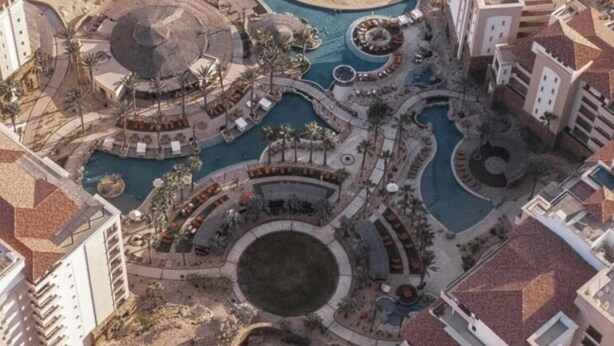 An aerial view of a resort with multiple swimming pools, beachfront, and buildings with red-tiled roofs. - Grand Solmar Cabo - Ocean front- Dining Area & Living Room (Cabo San Lucas)