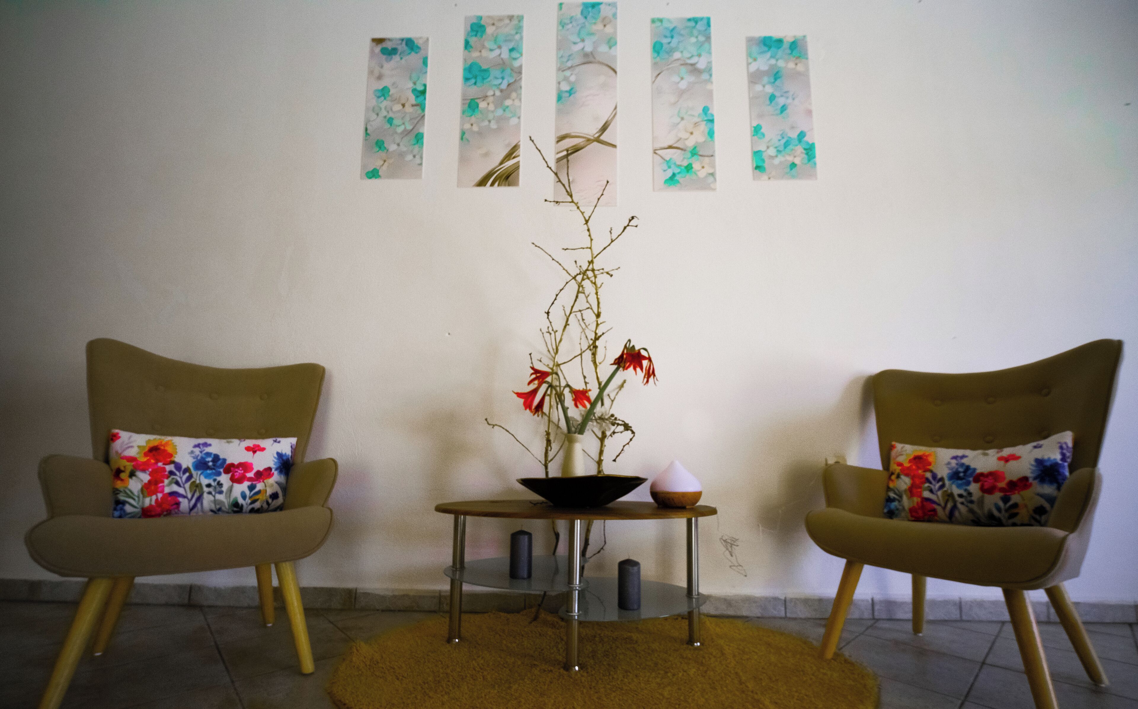 Una habitación con dos sillones, una mesita y un florero con flores.