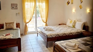 A hotel room with two beds, a wooden bench, a table with a towel, and a ceiling light fixture. - Aegli Hotel Studios (Thasos)