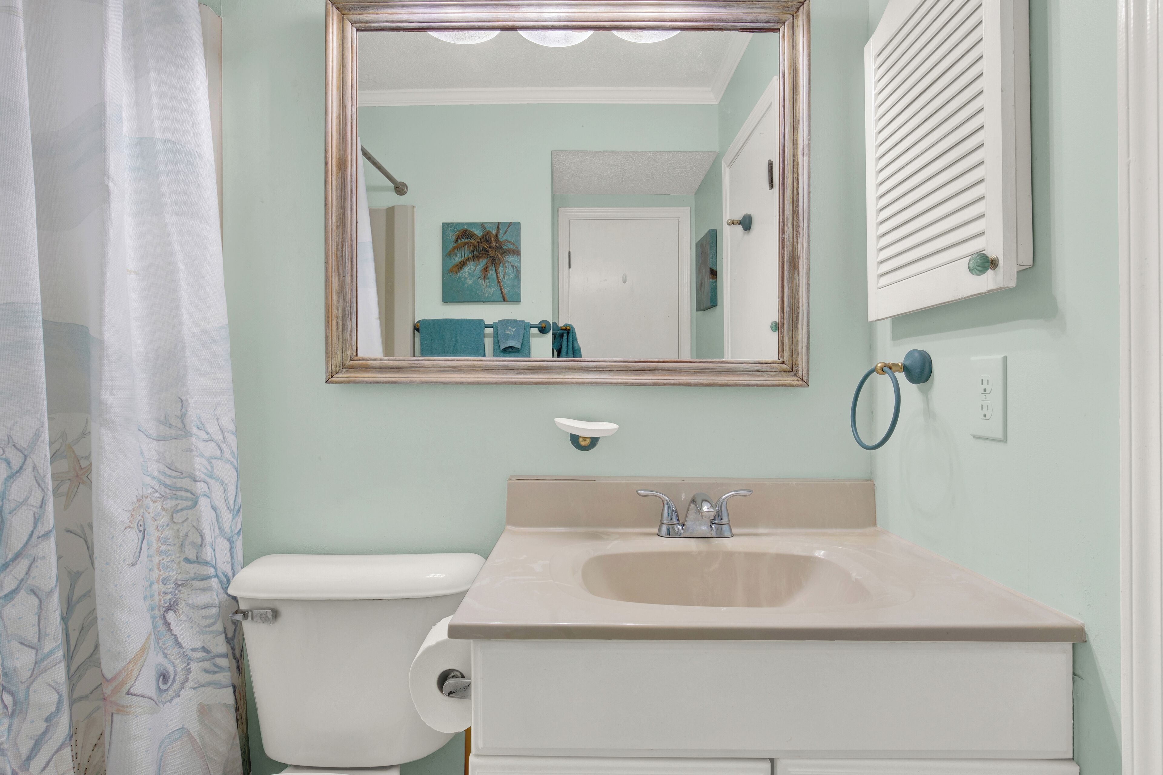 A bathroom with a toilet, sink, and mirror.