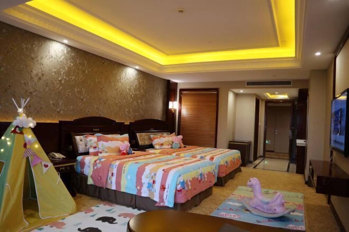 Una habitación de hotel con una cama, una tienda de campaña, un caballo de juguete y un televisor.