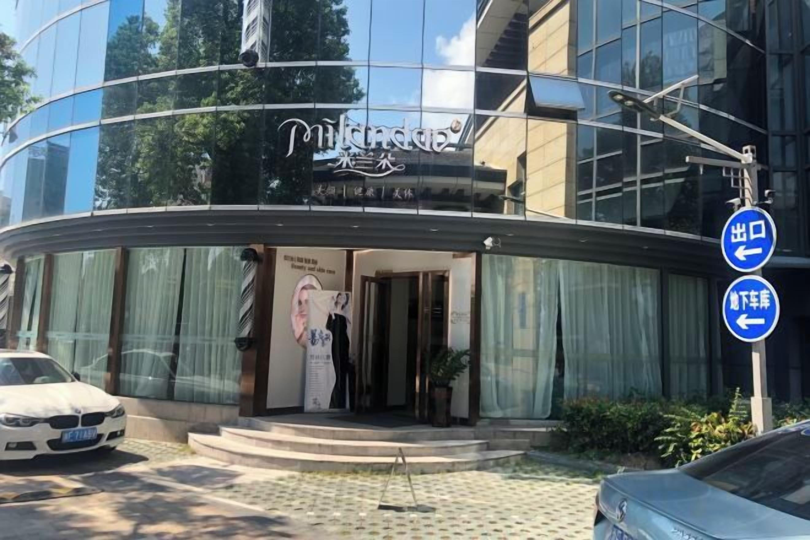 A modern hotel with a curved glass facade, a visible entrance, and a sign indicating a restaurant.