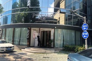 A modern hotel with a curved glass facade, a visible entrance, and a sign indicating a restaurant. - Haiyan Hotel (Haiyan)