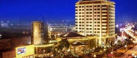 A hotel with a prominent tower, a large building with a dome, and a well-lit street at night.