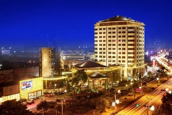 A hotel with a prominent tower, a large building with a dome, and a well-lit street at night.