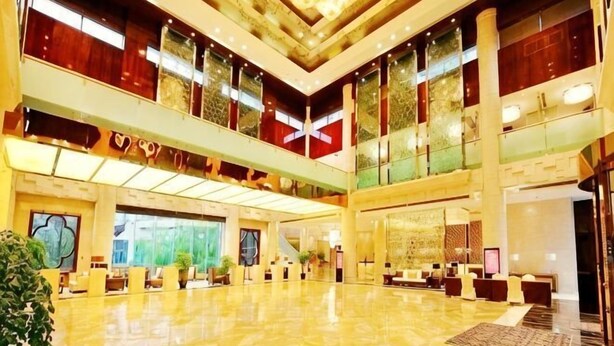 A spacious lobby with a high ceiling, multiple seating areas, and large windows.