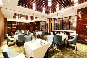 A hotel dining area with tables set for service, a patterned carpet, and a modern ceiling design. - Haiyan Hotel (Haiyan)