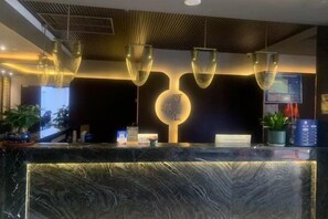 A reception area with a marble counter, pendant lighting, and a digital screen. - Haiyan Hotel (Haiyan)