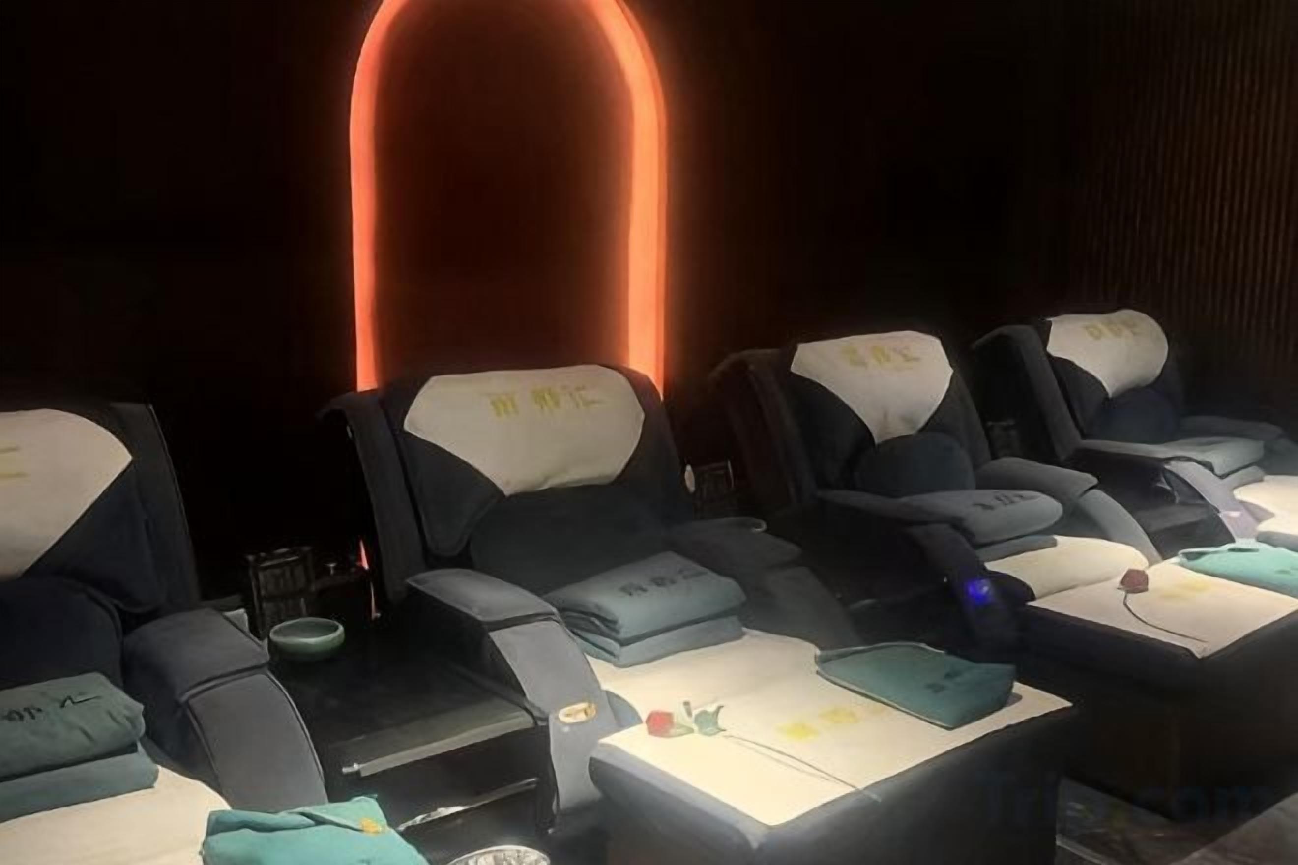 A row of reclining chairs with headrests and a table in front, likely in a lounge or relaxation area.