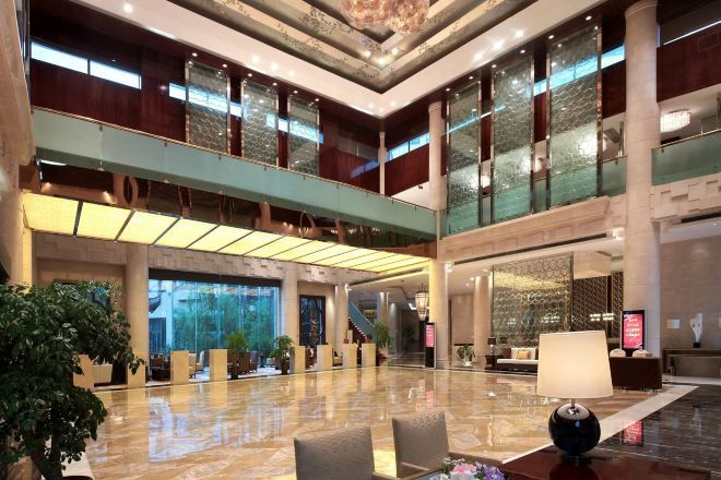 A spacious lobby with a high ceiling, large windows, and a central seating area.