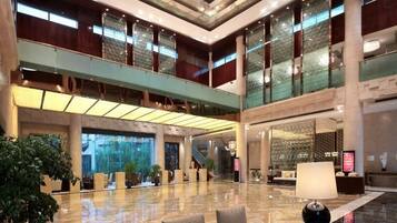 A spacious lobby with a high ceiling, large windows, and a central seating area.