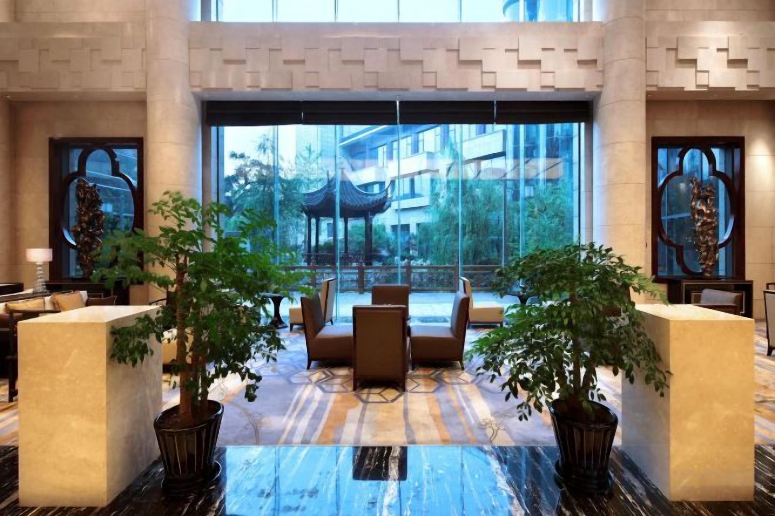 A lobby with a reception desk, seating area, and large windows offering a view of the outside.
