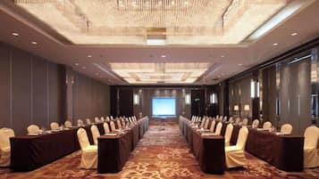A conference room with a long table, chairs, and a large screen at the front.