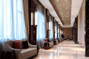 A hotel lobby with a row of sofas and armchairs, a long corridor, and a large window with curtains. - Haiyan Hotel (Haiyan)