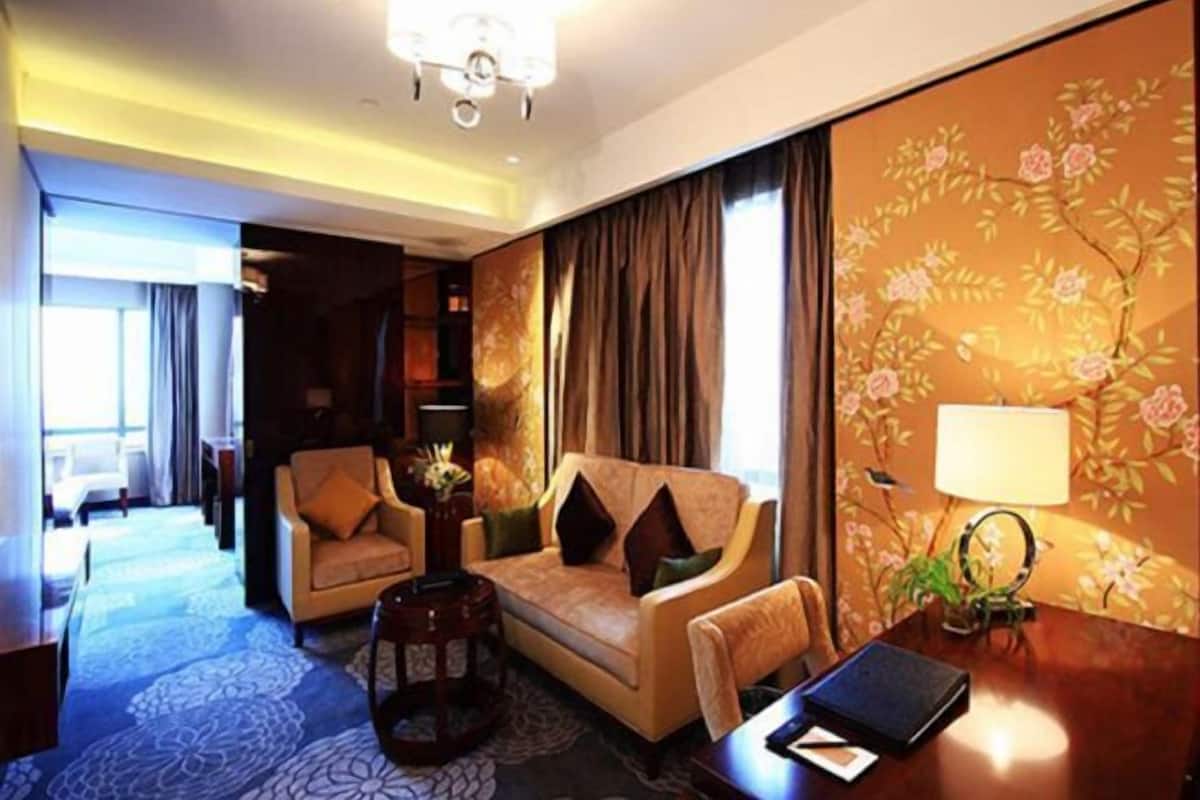 Habitación de hotel con sofá, sillón y una pequeña mesa con lámpara.