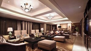 A spacious living room with a large sofa set, a coffee table, and a chandelier.
