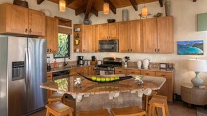 Una cocina con gabinetes de madera, electrodomésticos de acero inoxidable y una isla central con taburetes.