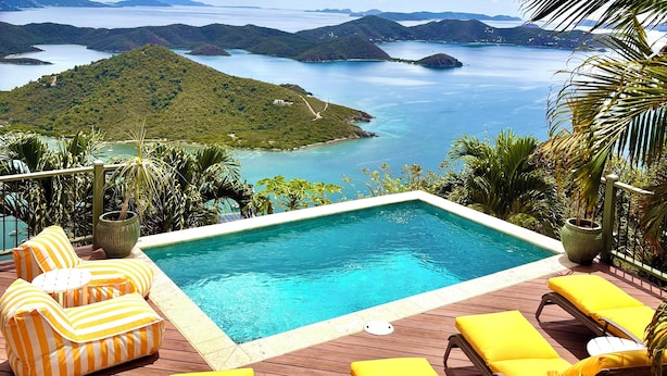 Zona de piscina con sillones de descanso y vistas al mar y a las islas.