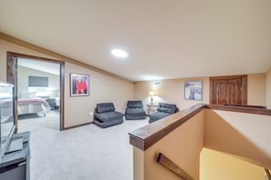 A spacious room with a large bed, a desk, and a chair. There are three armchairs and a small table with a lamp. The room has a wooden ceiling and a door with a window. - Hunt, Fish & Enjoy the Outdoors: Rural Atoka Home (Atoka)
