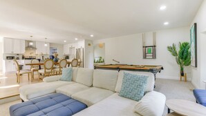 Una sala moderna con un sofá, mesa de billar y comedor.