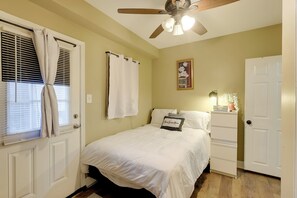 A bedroom with a bed, a ceiling fan, a nightstand, and a door. - 1 Mi to Dtwn Wilmington: Convenient + Cozy Home! (Wilmington)